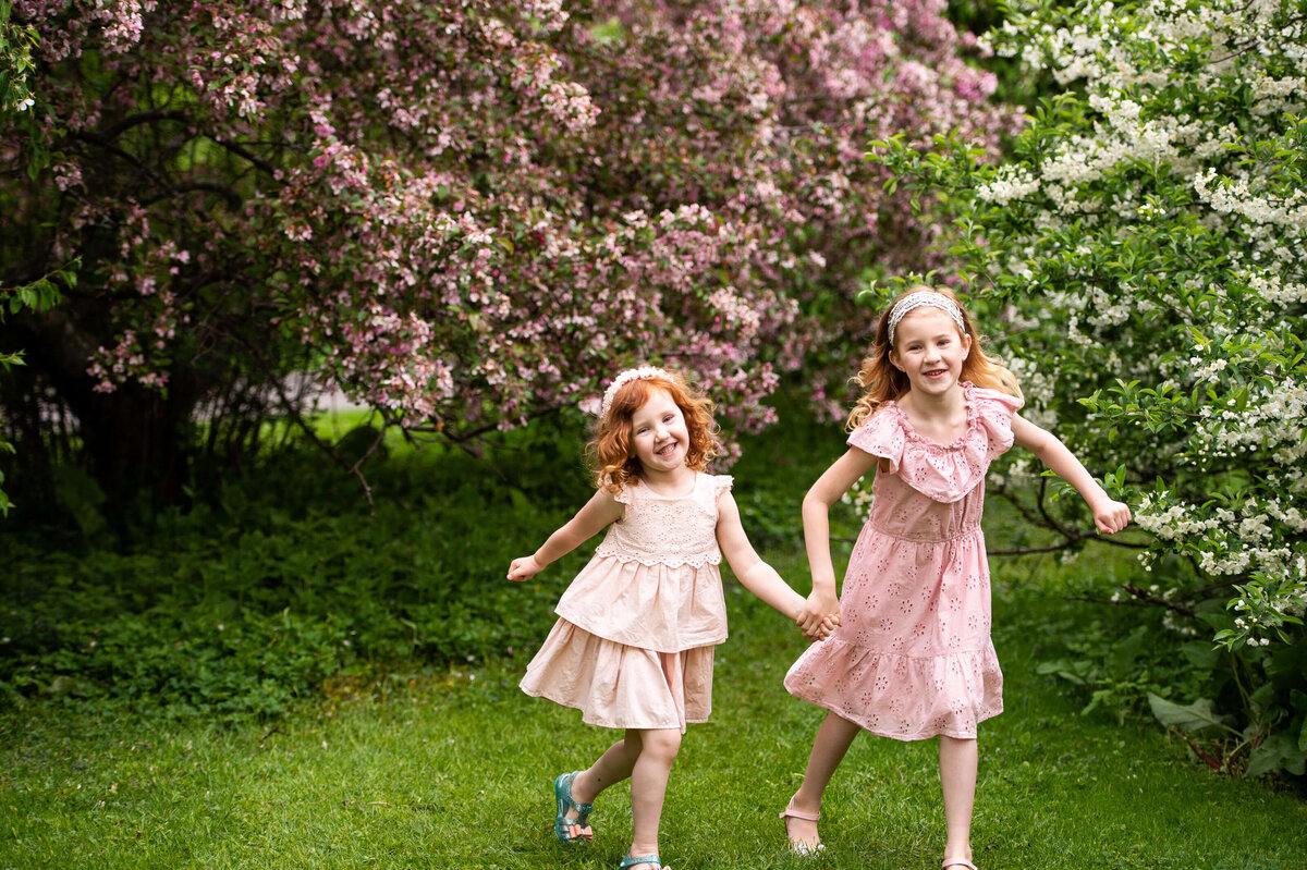 Ottawa family photography of two little girls wearing pink running and holding hands