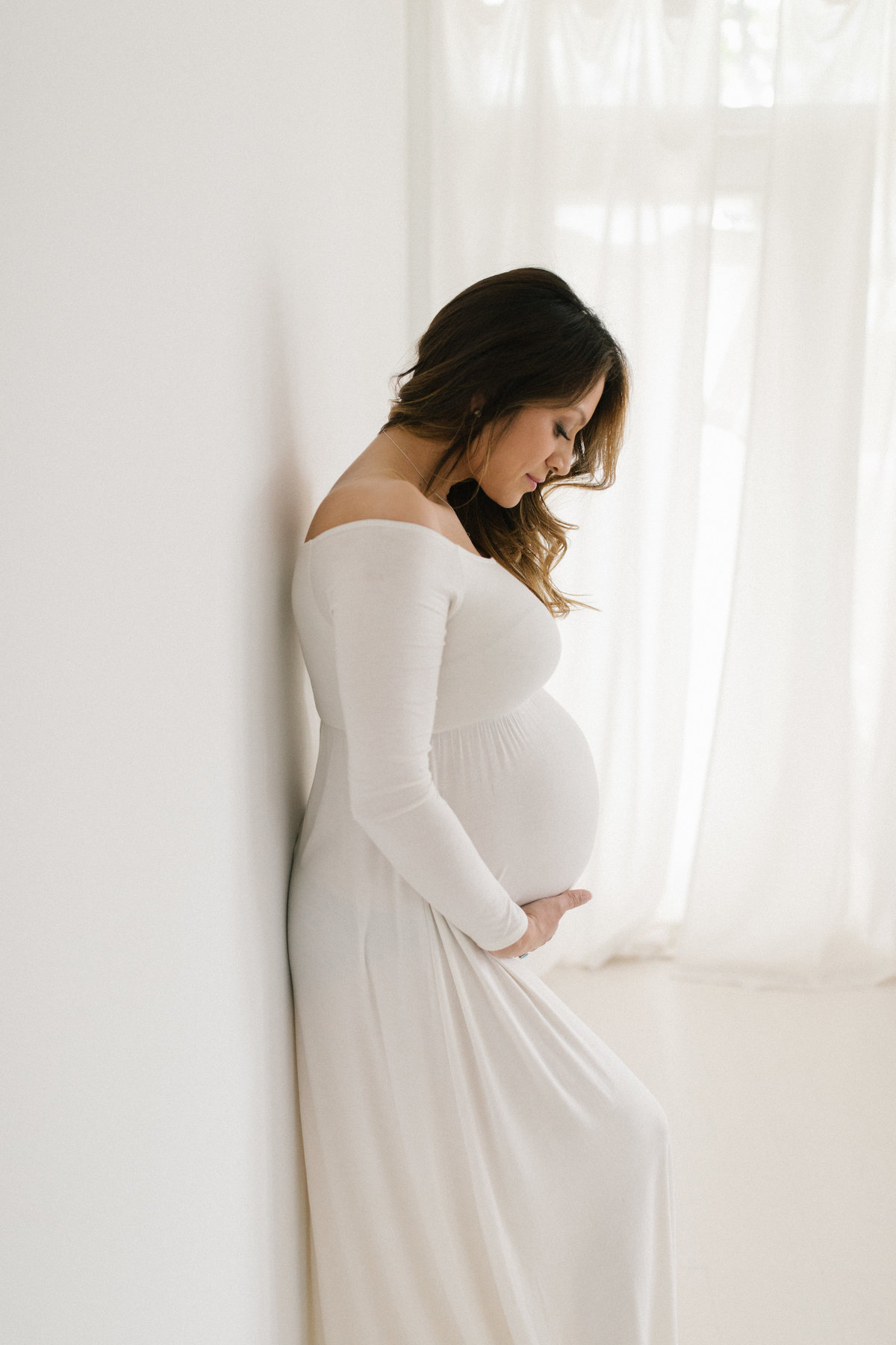 Chicago maternity photographer Elle Baker Photography photographs a woman in a long white dress in her natural light studio