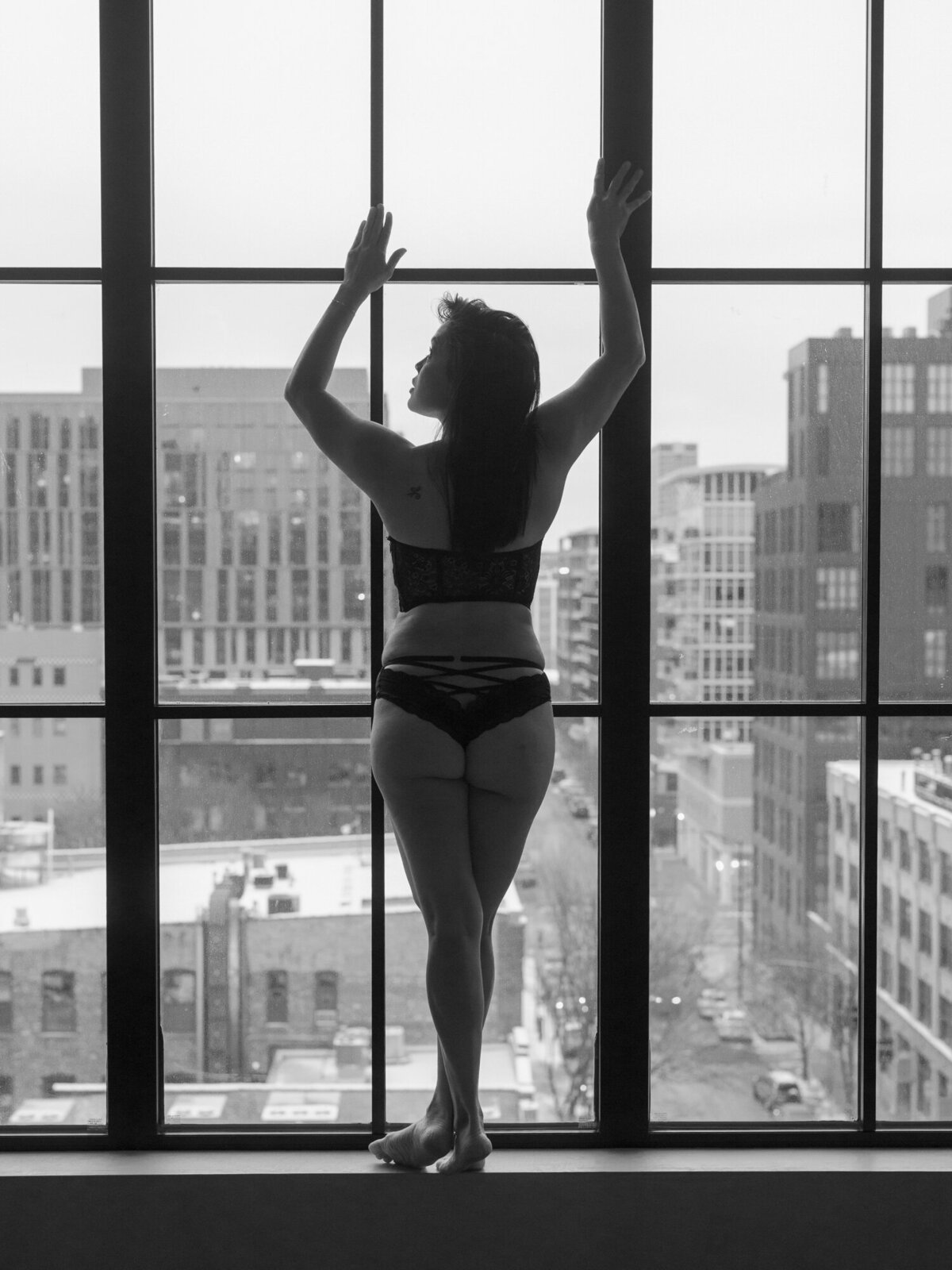 A woman poses for a boudoir photo at the Nobu Hotel in Chicago with the West Loop neighborhood in the backdrop