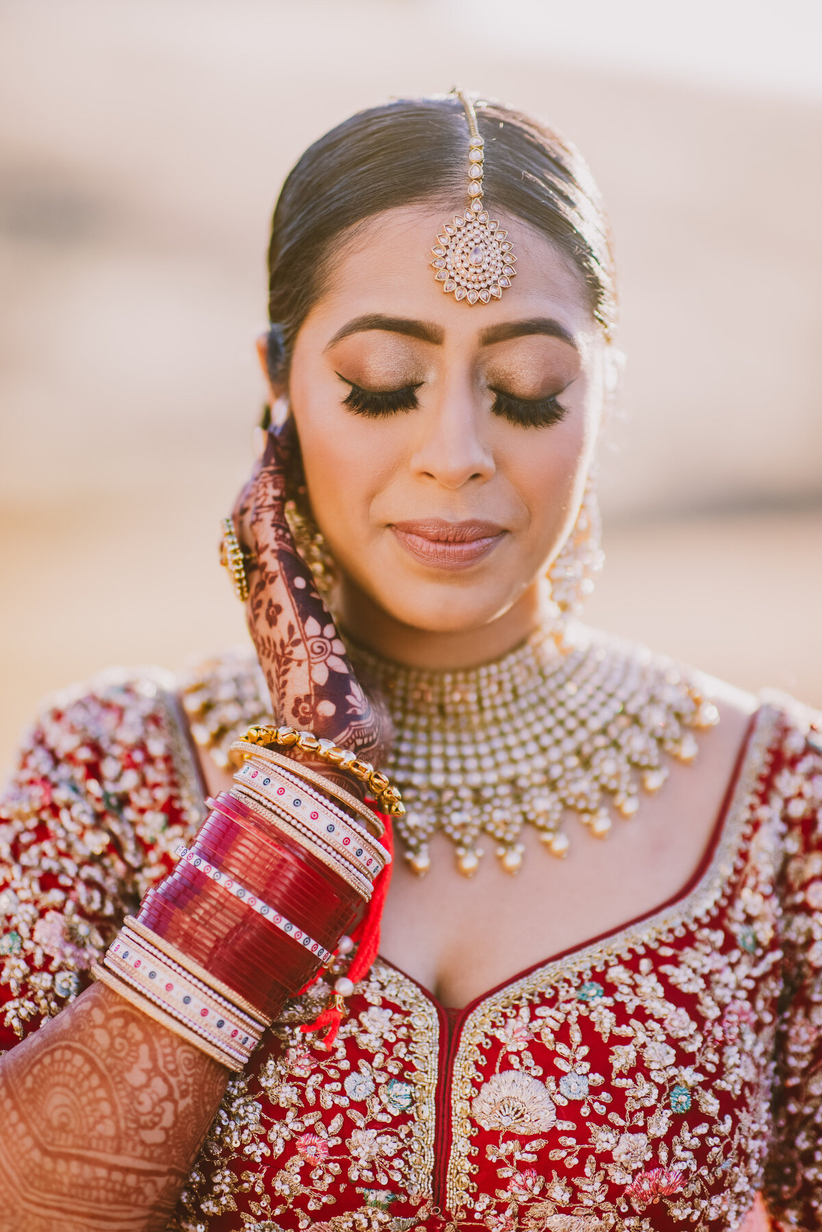 An indian sikh bride with her eyes closed while getting ready for her anand karaj wedding ceremony in sacramento