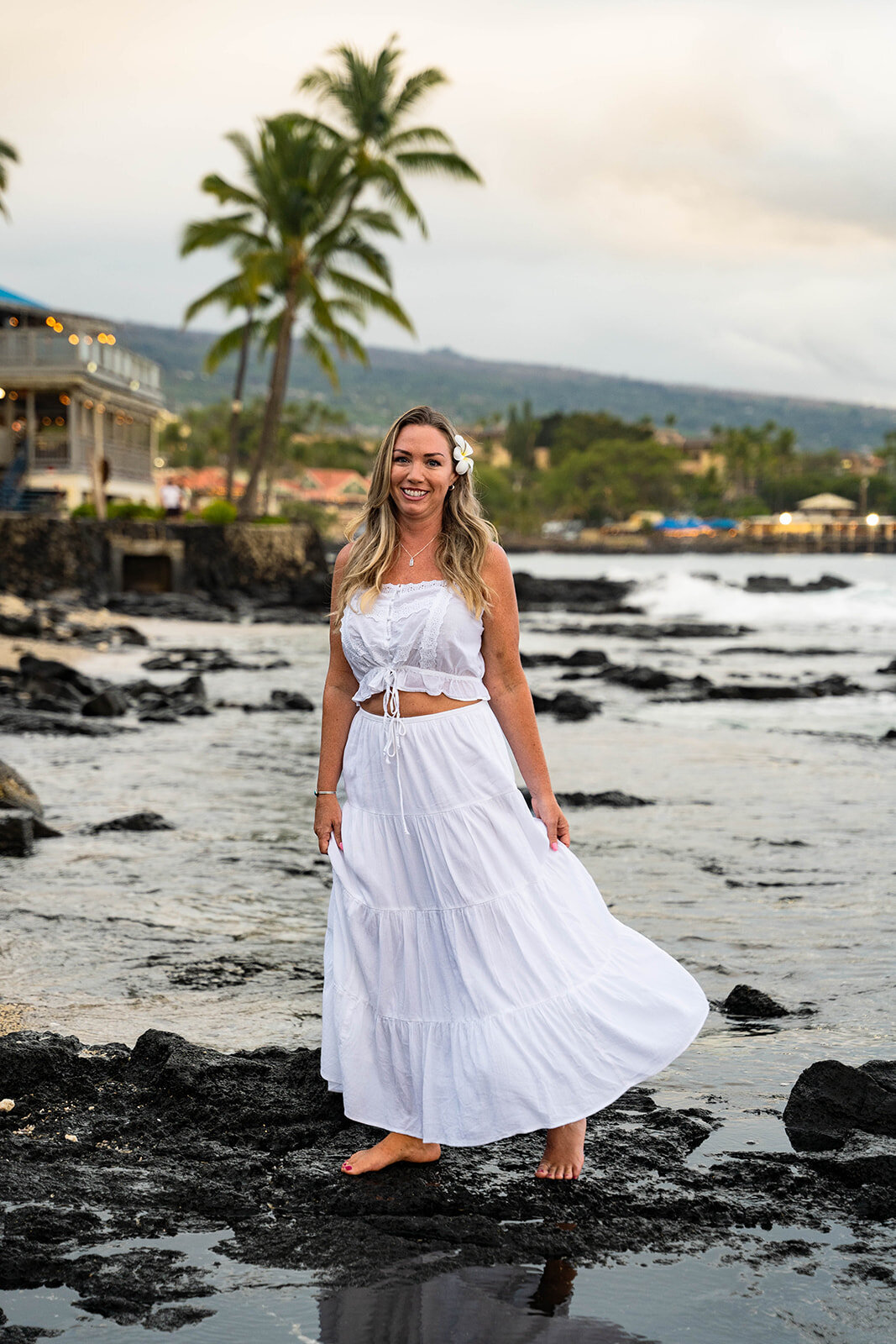 Woman wearing white dress standing near the ocean for hawaii portrait photography