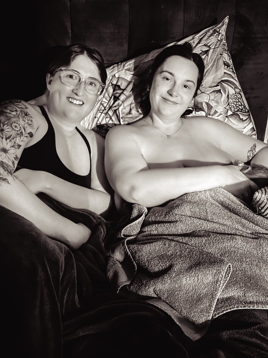 lesbian couple smile after the birth of their child