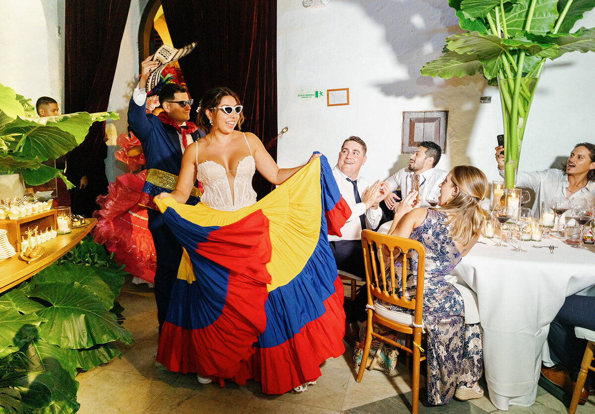 Victoria surprises guests by entering the reception wearing a vibrant Colombian flag-inspired dress, celebrating her heritage.
