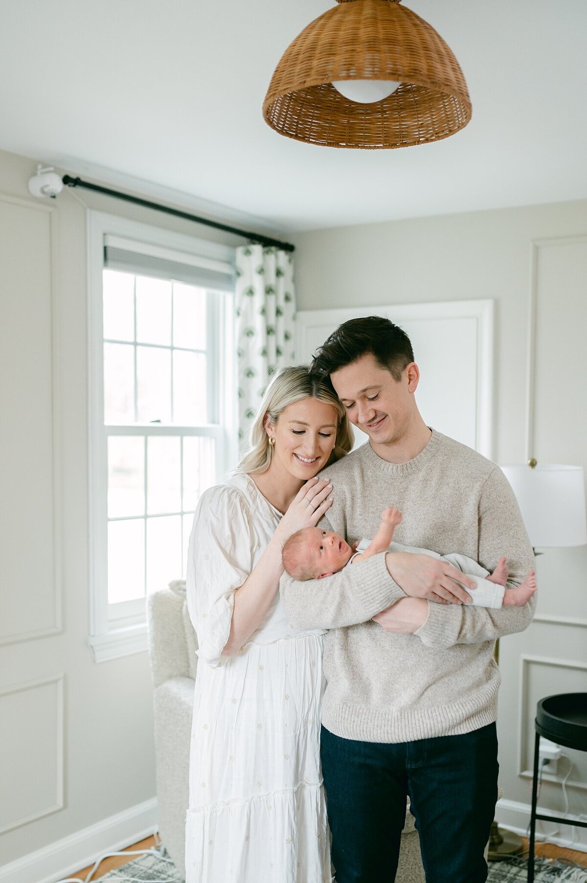 Mom snuggles into her husband's shoulder while he cradles their baby