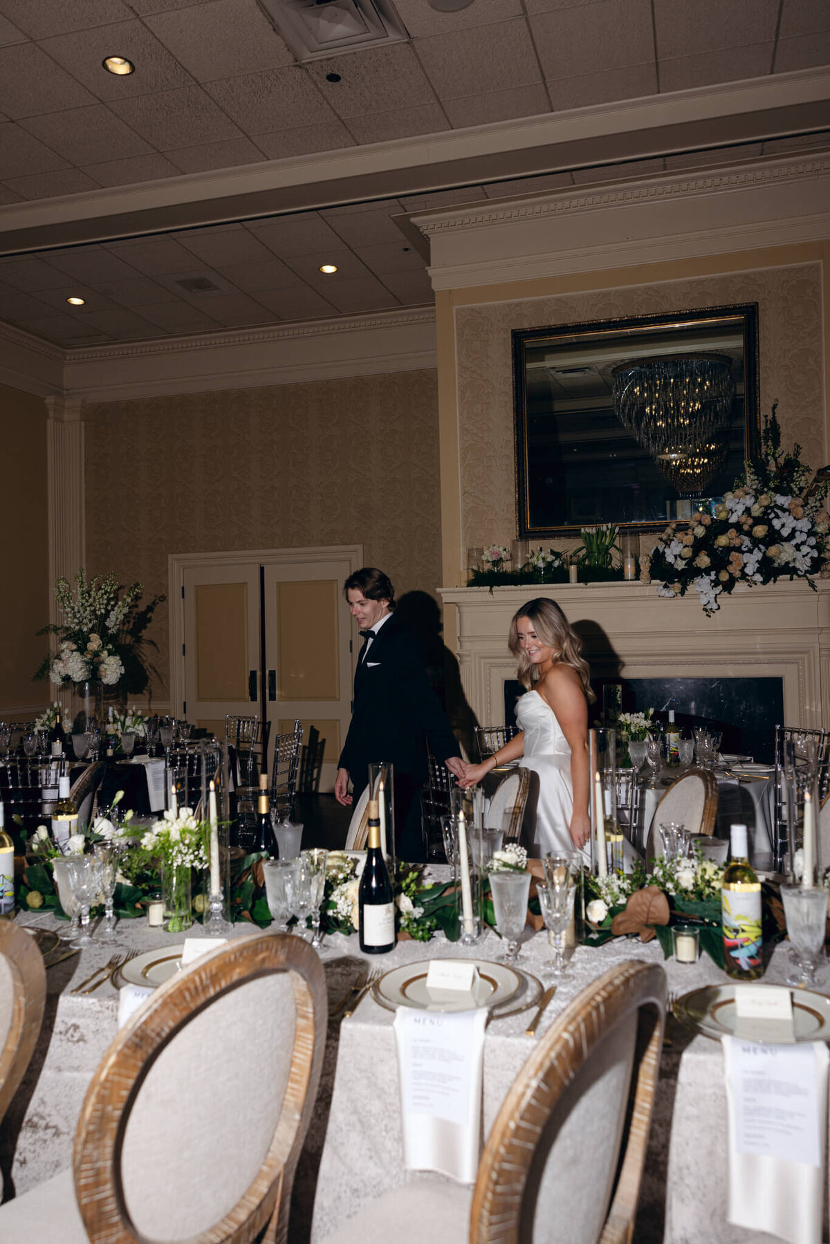 A wedding photo of the bride and groom walking through the reception hall admiring the decorations