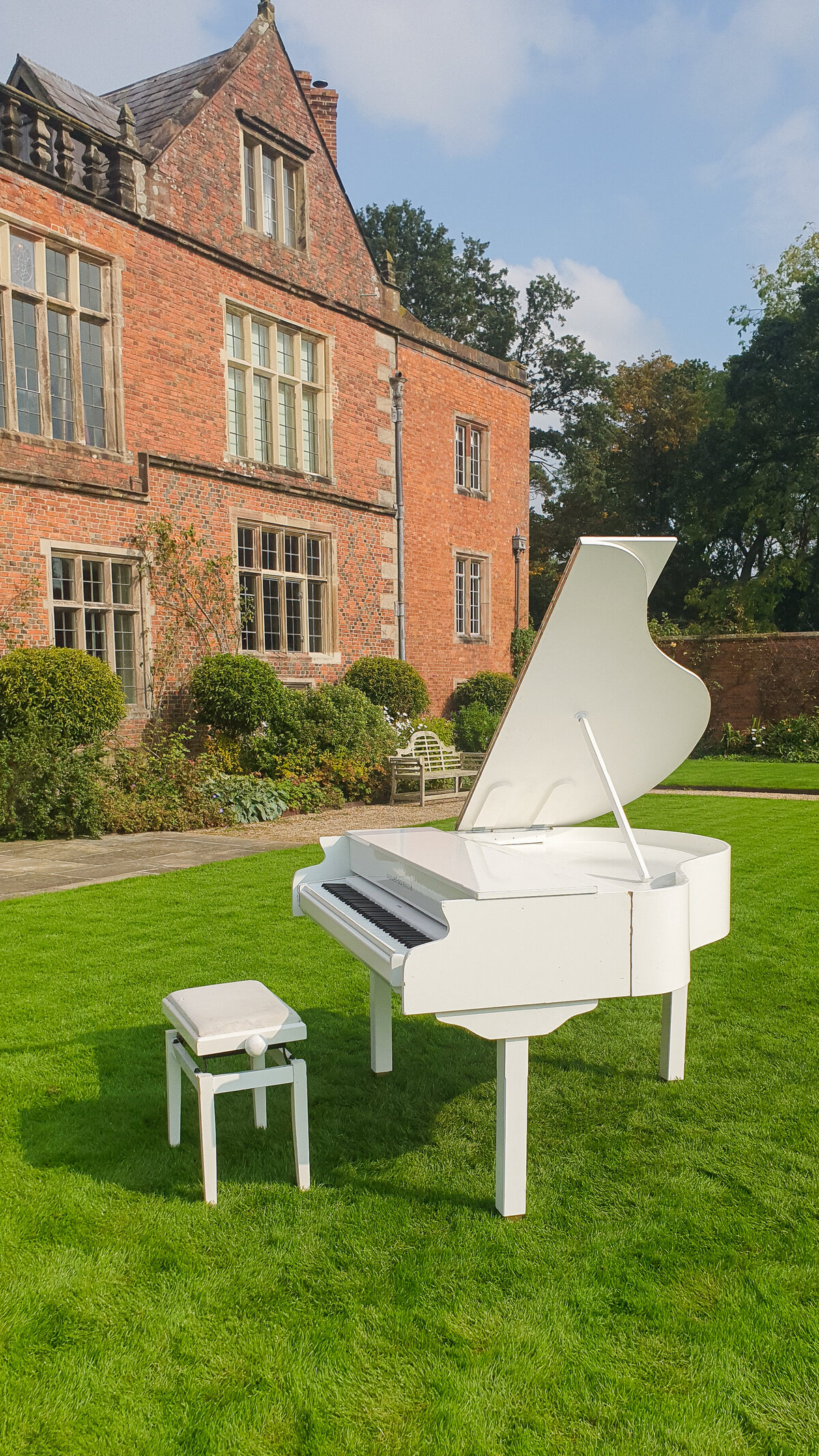 white baby grand piano outside wedding ceremony