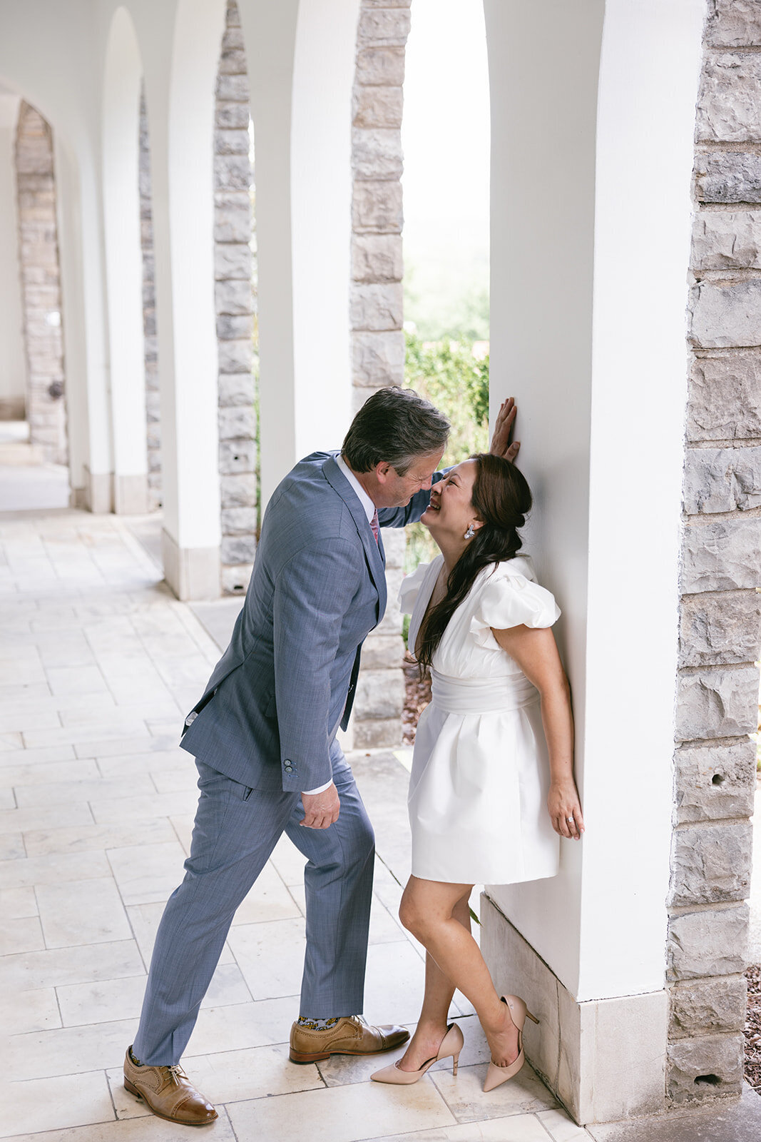 Bride and groom share smiles along an arched hallway at the Cheekwood Mansion. 