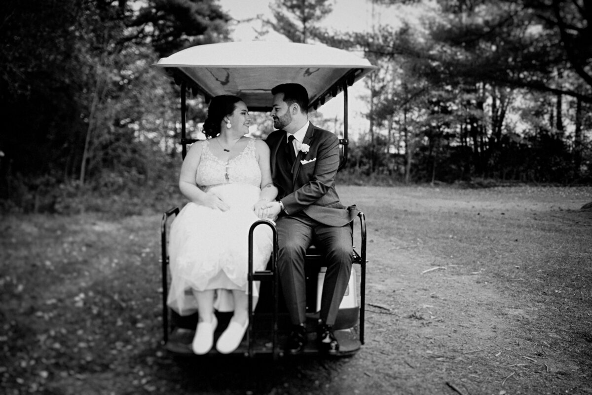 black-and-white-image-of-newlyweds-at-the-back-0f-a-golf-cart-at-bean-town-ranch-ottawa-1