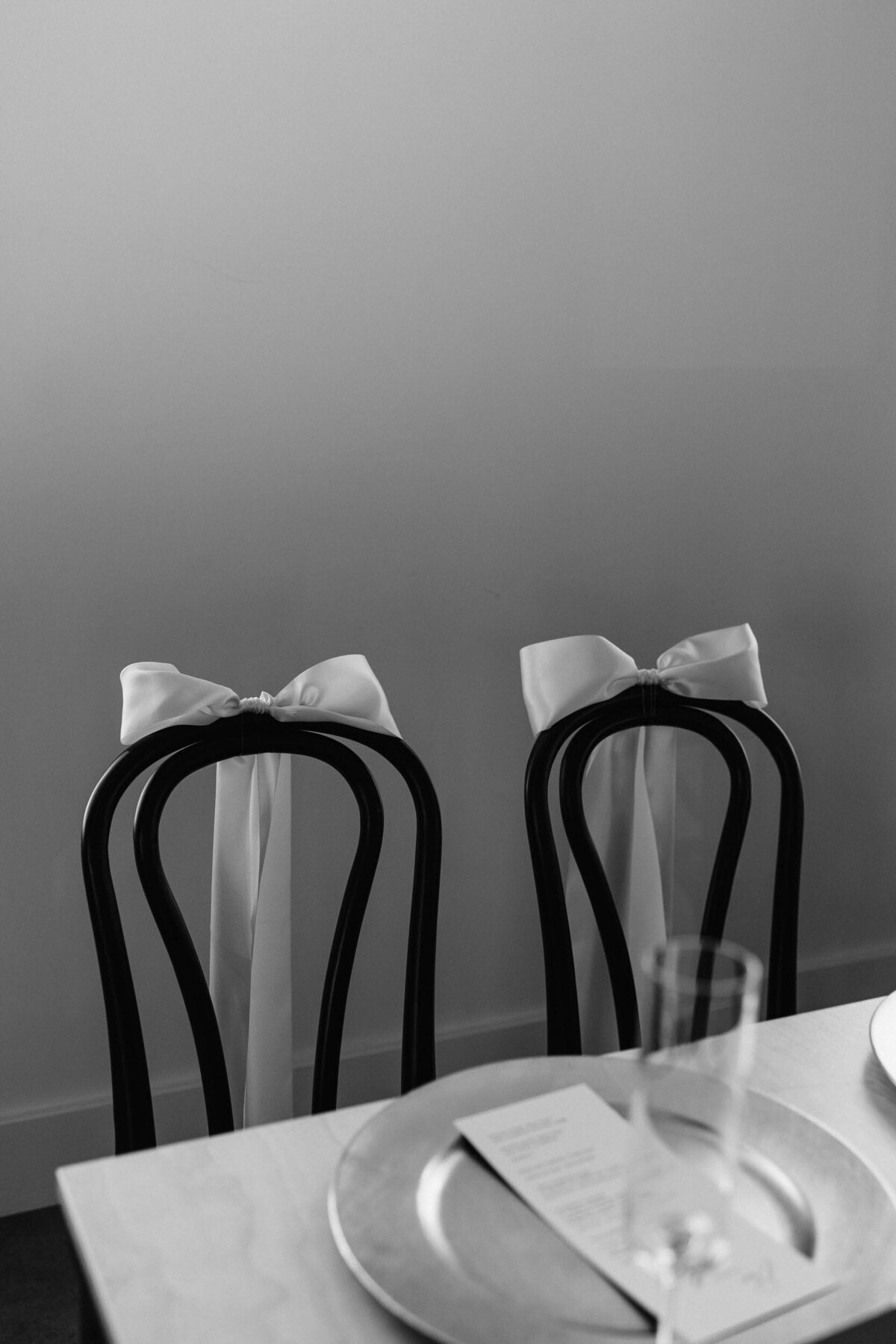 Two chairs with bows on top of them