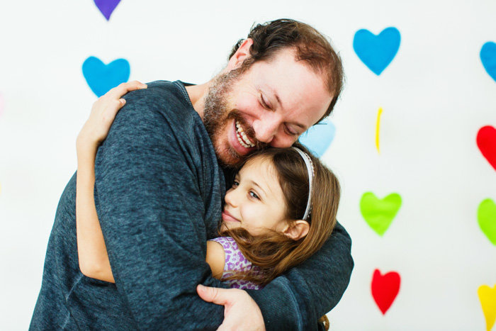 Shot of dad hugging daughter in front of heart backdrop