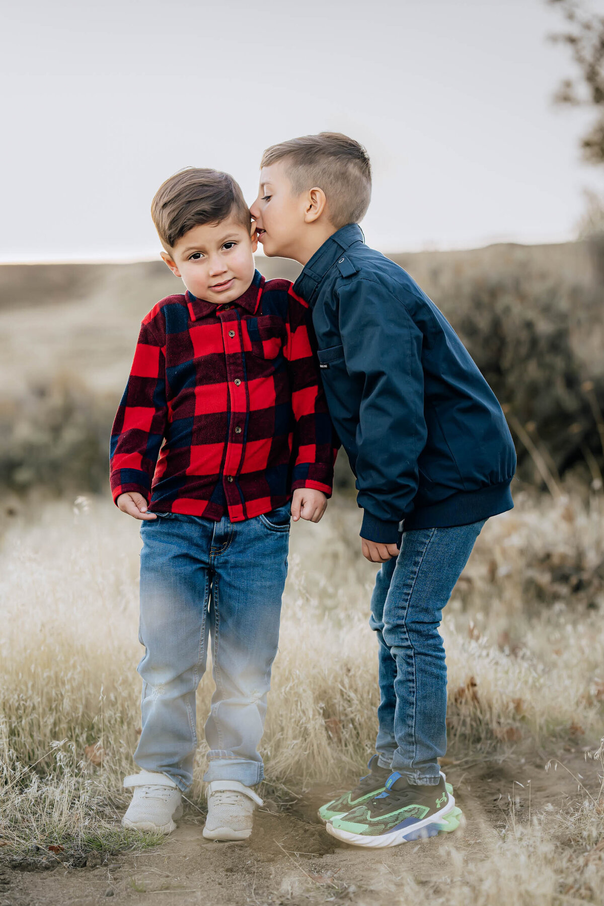 Sweet moment of a brother whispering to his sibling during a family session in Sammamish, WA, full of curiosity and connection.