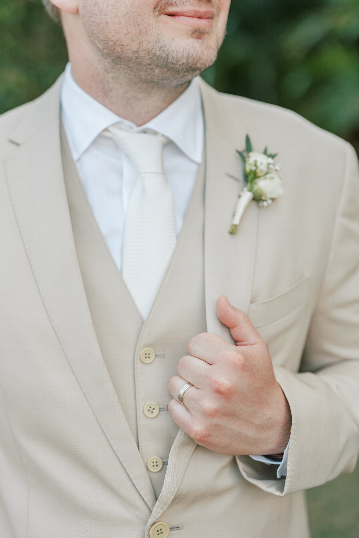 Close-up of groom’s boutonniere and wedding ring in Cancun, Mexico, wedding photo.