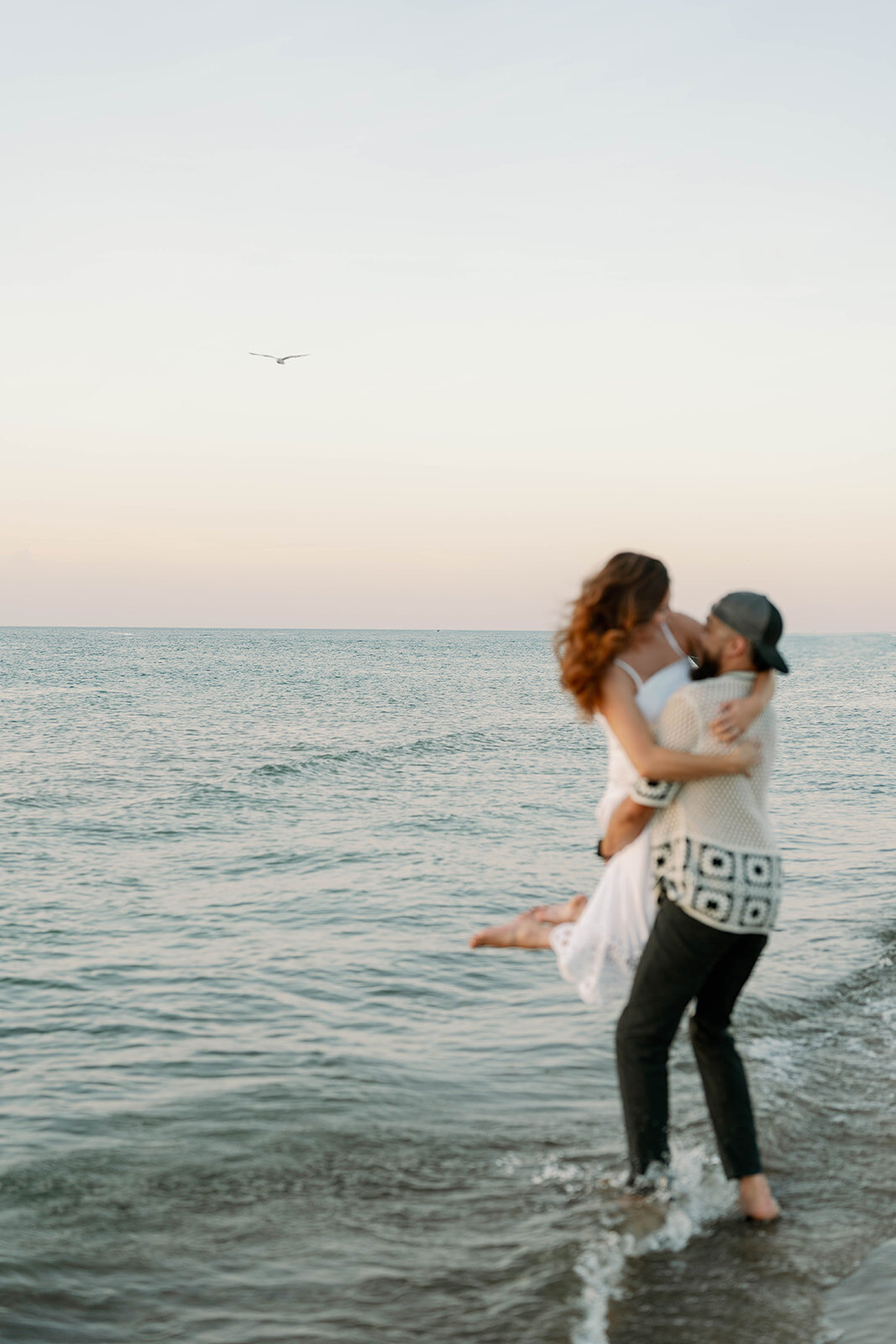 Engaged couple walking barefoot along Lake Michigan shoreline at New Buffalo Beach in Michigan