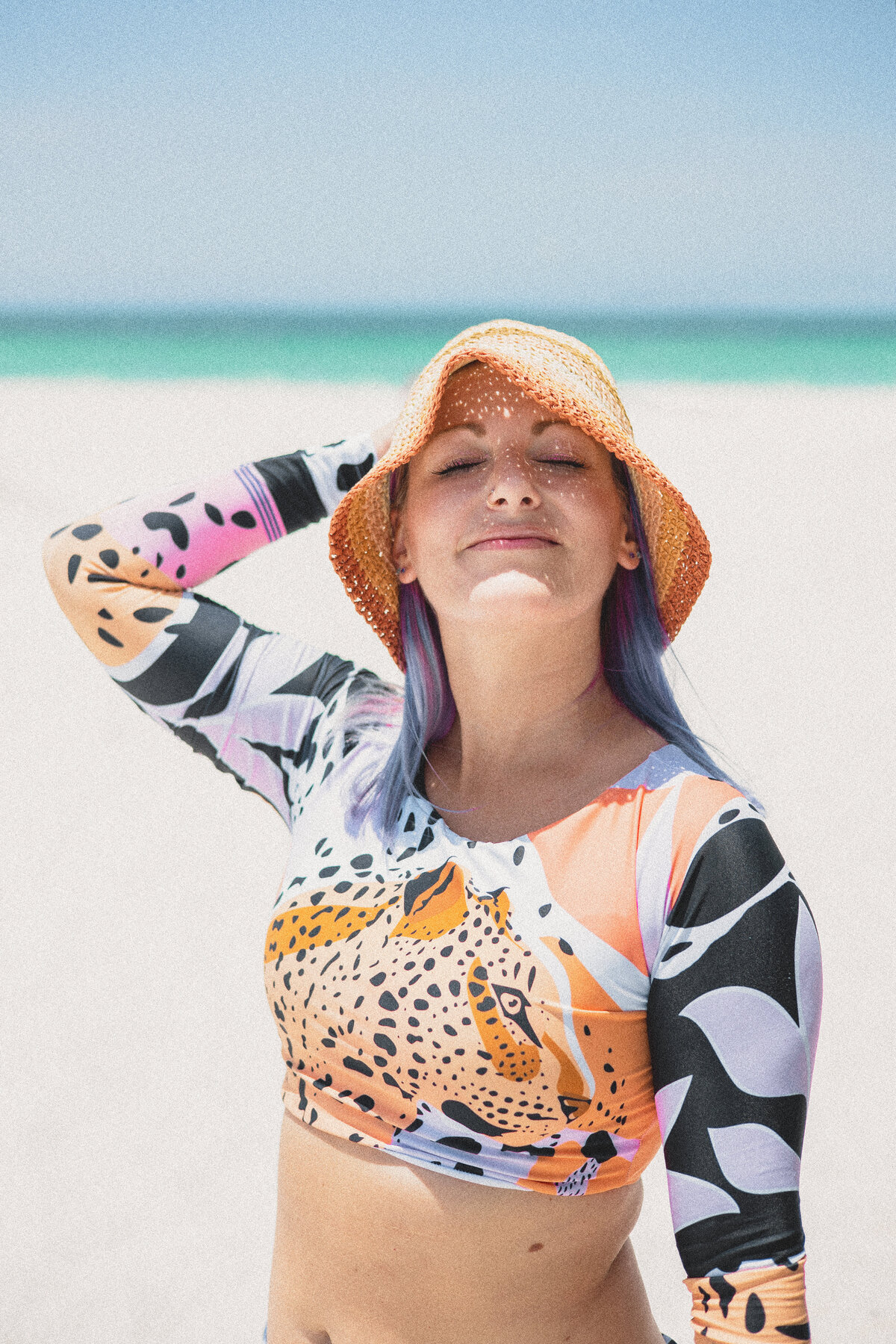 Model wearing woven bucket hat and surf rash guard standing in the sun