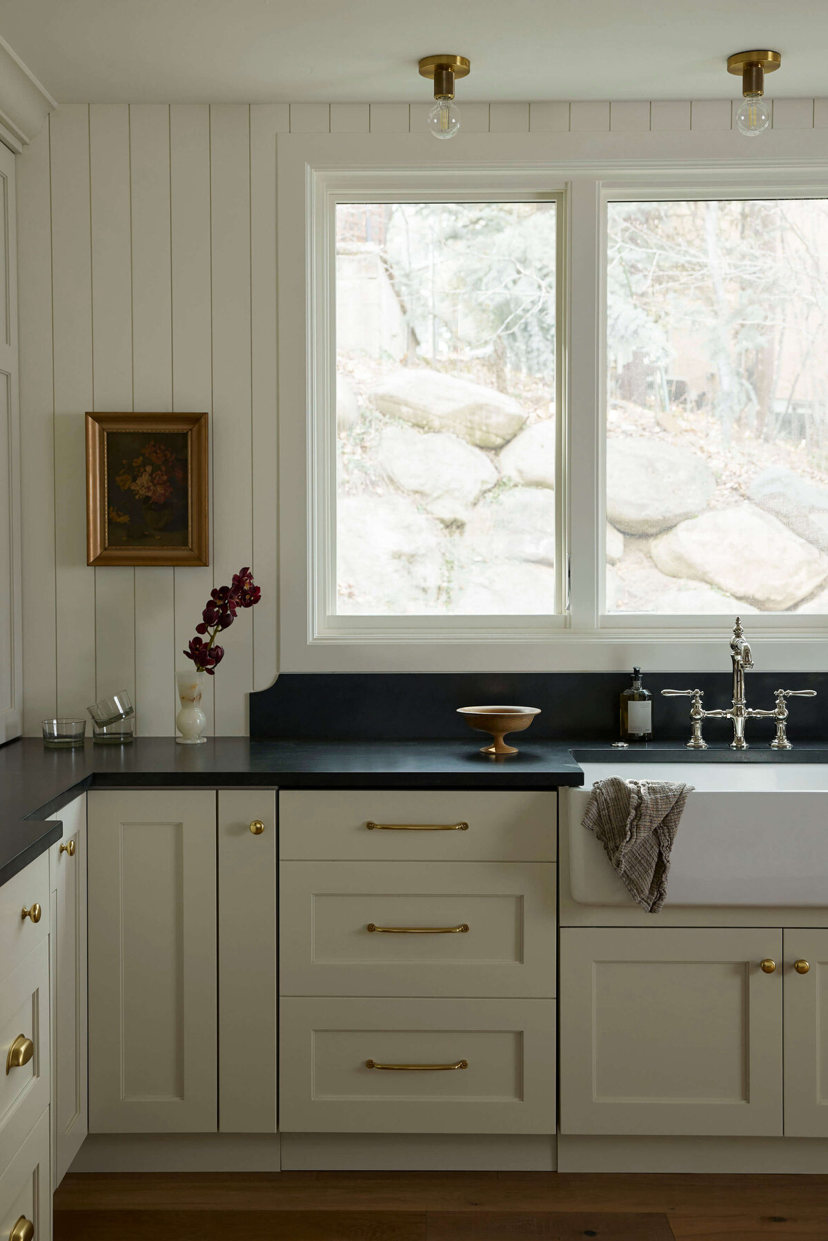 farmhouse-sink-black-countertops-brass-hardware-kitchen