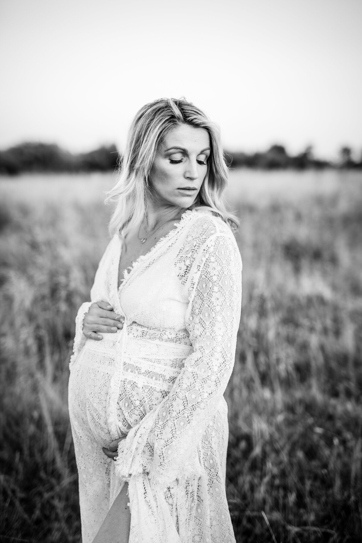 Black and white photo of a pregnant woman in a lace dress