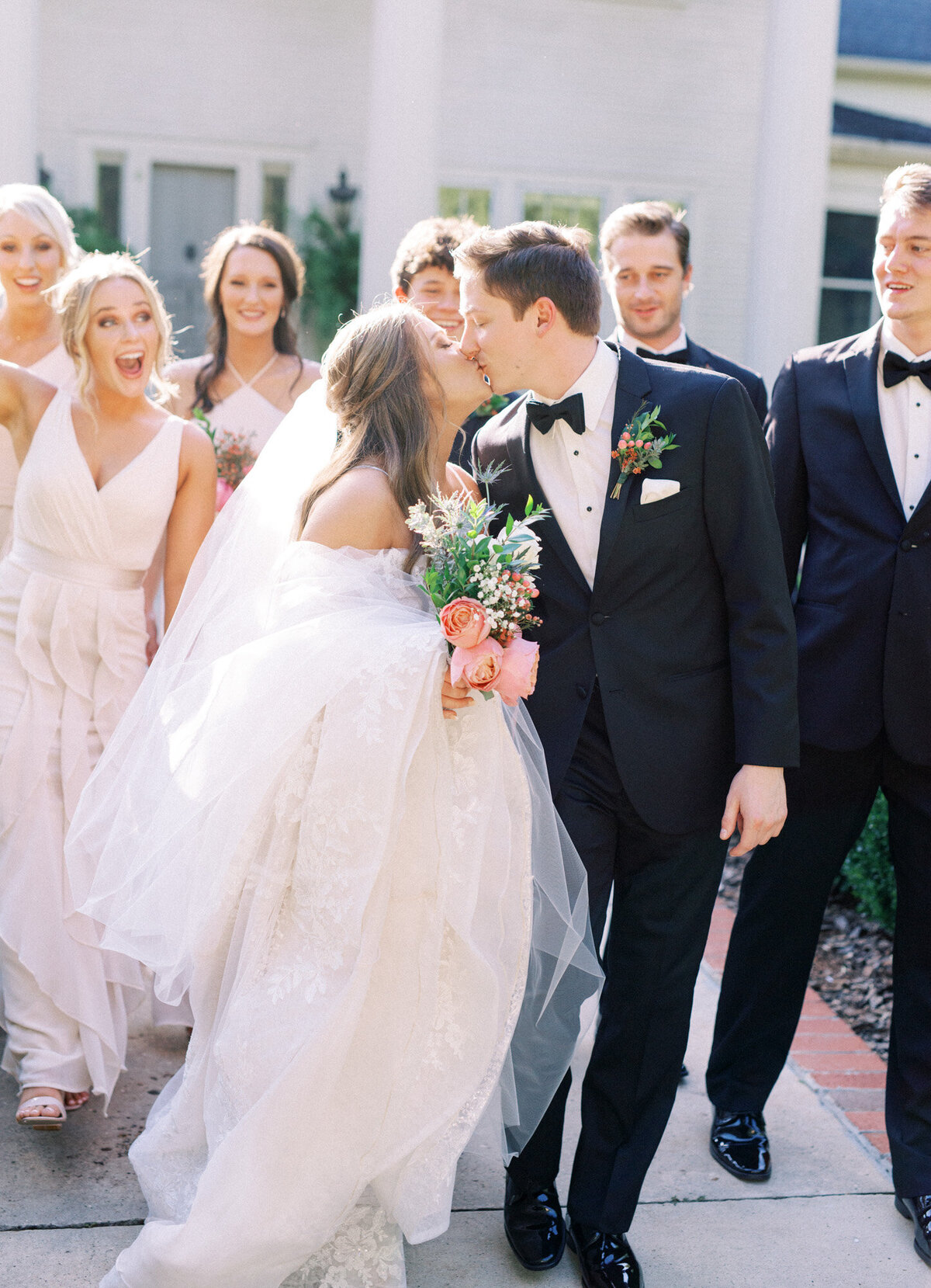A bride and groom share a kiss in front of their wedding party by Chattanooga wedding photographer, Kelsey Dawn Photography