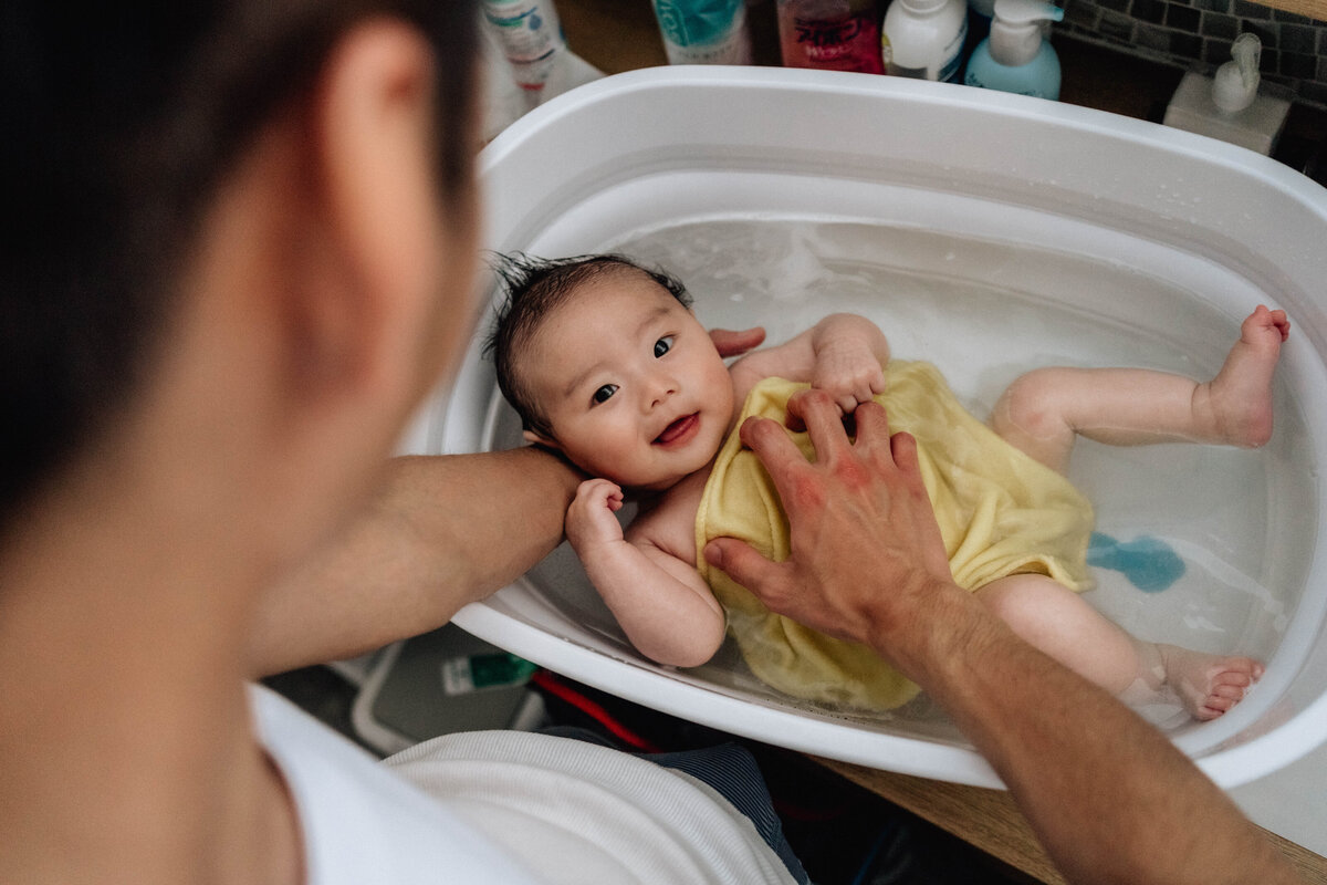 お父さんが新生児の沐浴をしている写真
