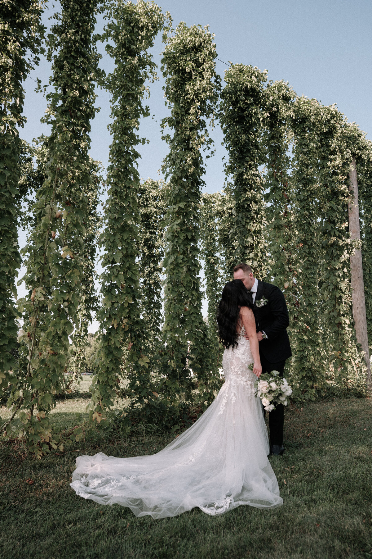 newlyweds share a kiss in front of the hopps farm