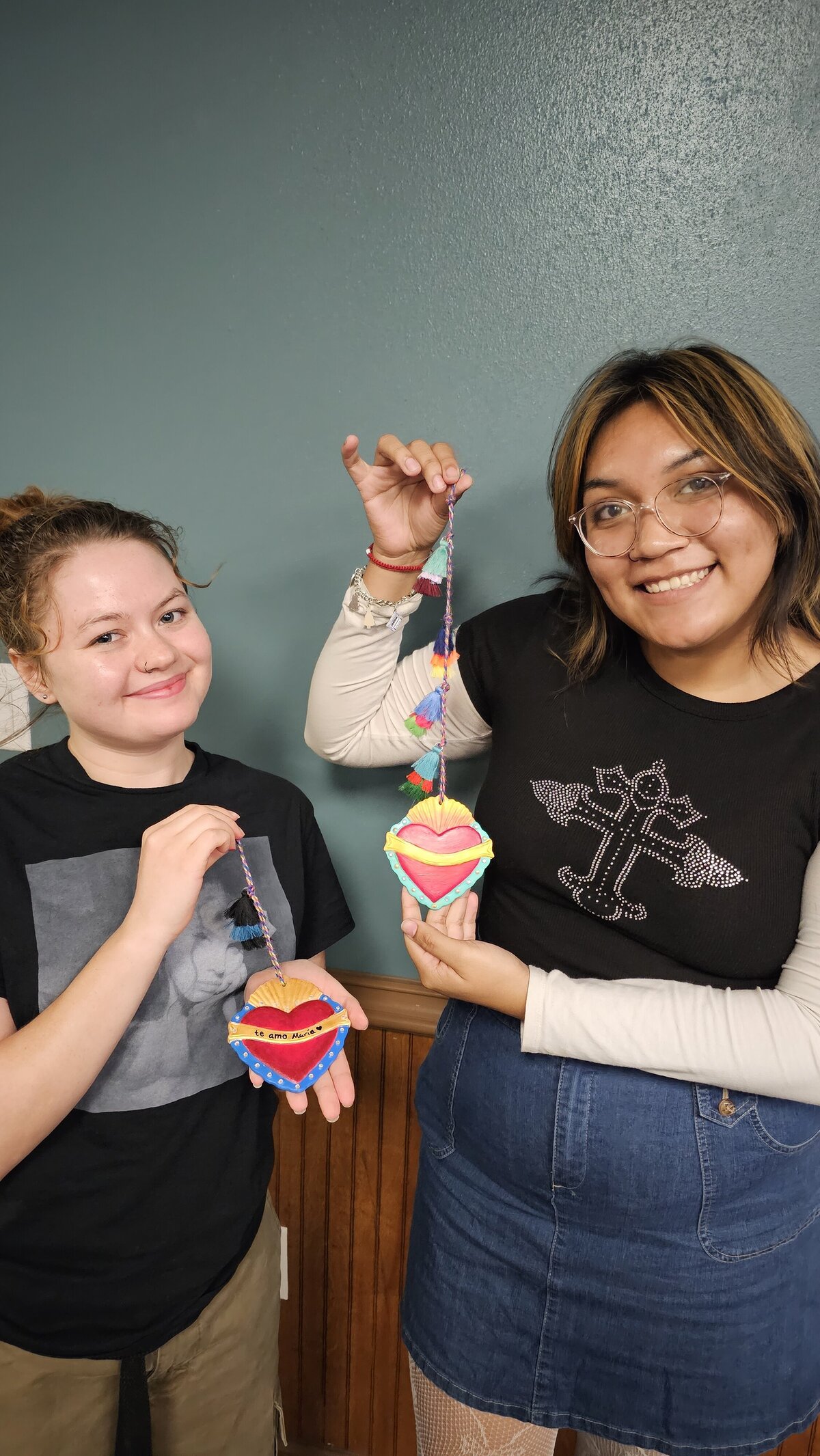 The dynamic creativity of two young artists as they proudly present their final artwork at Soleil Vida Studio's art workshop. Standing in front of the workshop room board, these girls crafted vibrant and expressive hearts, each telling a unique story.