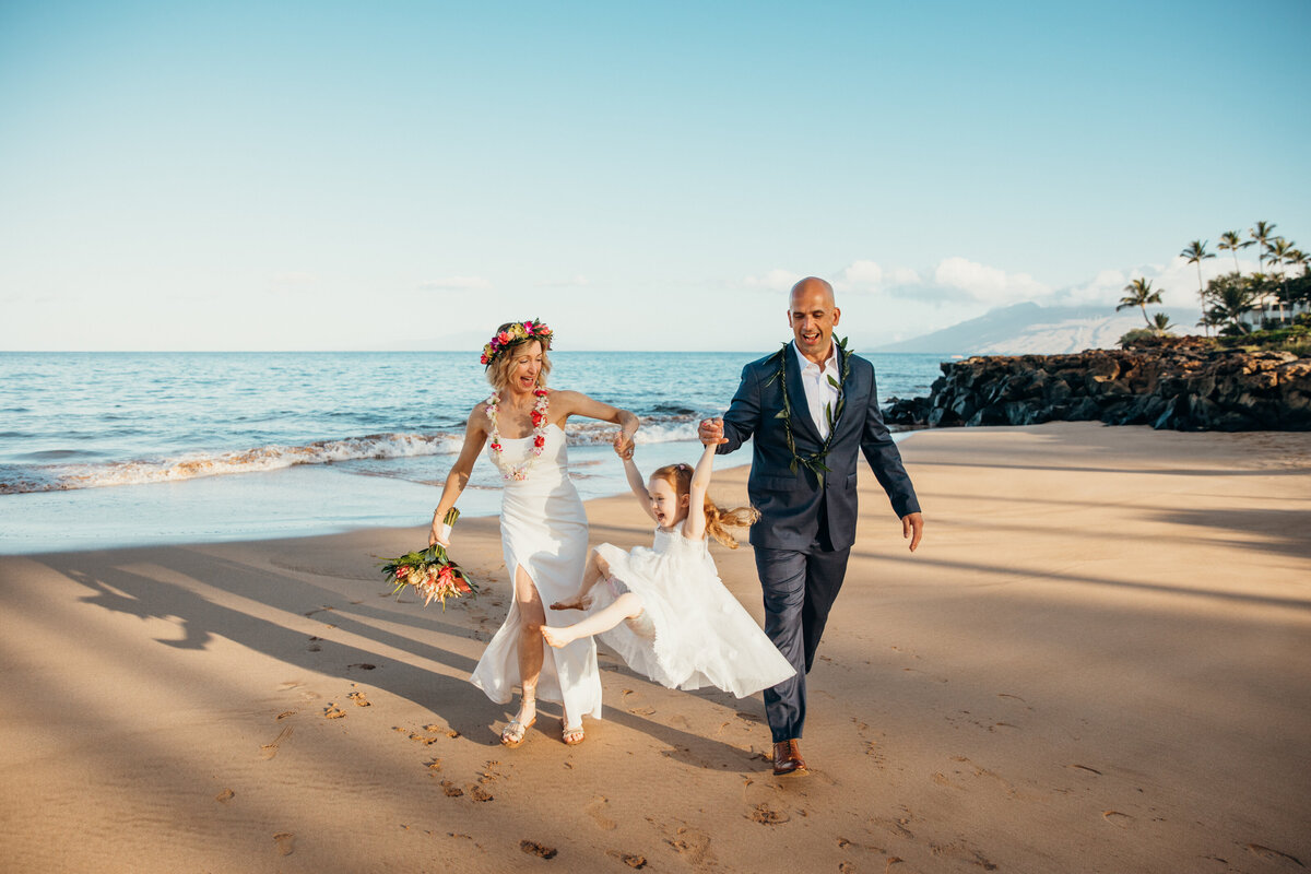 Maui Wedding Photographer captures bride and groom swinging child on beach