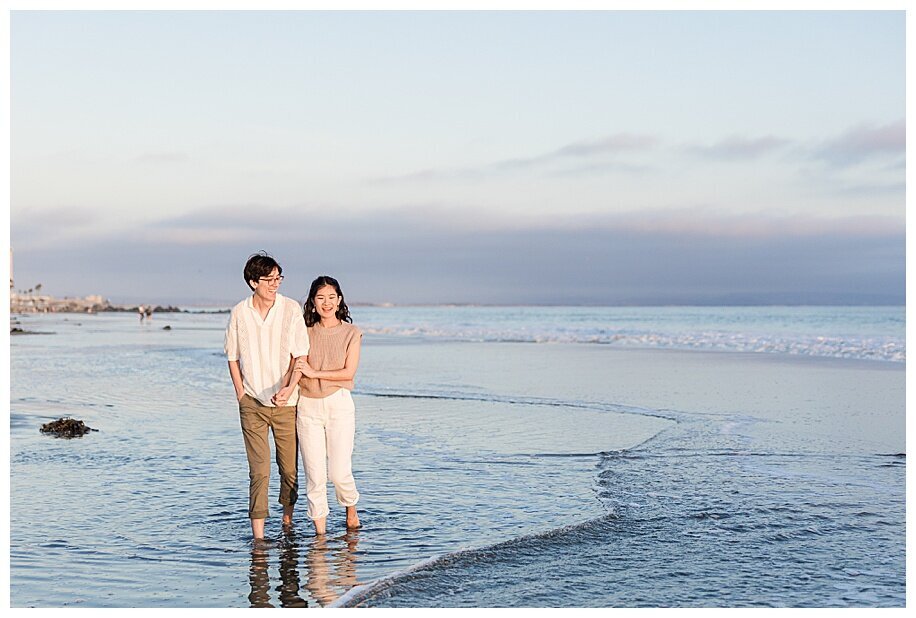 engaged couple walking in ocean at coronado beach