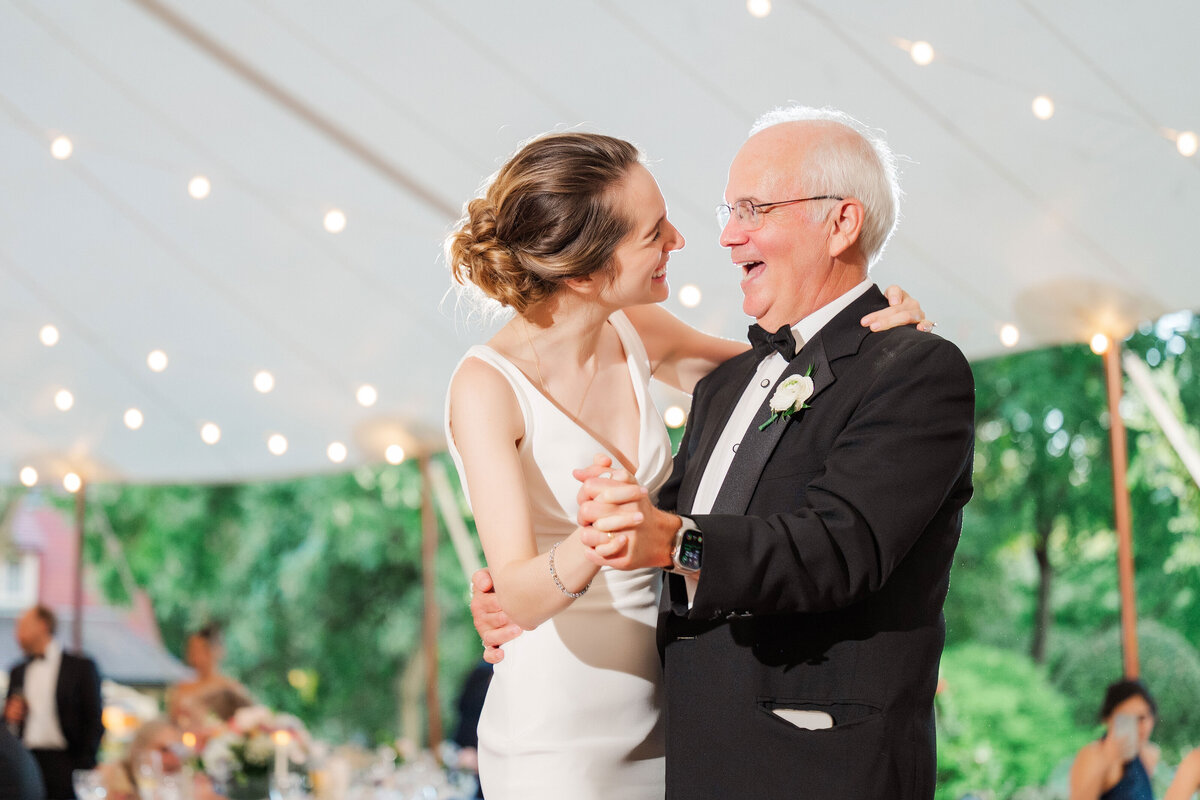 bride and dad dancing together under a tented wedding at Frick Museum in pittsburgh with twinkle lights behind them