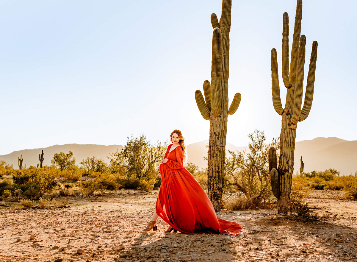 maternity mom in rust dress walking in AZ desert for photograph