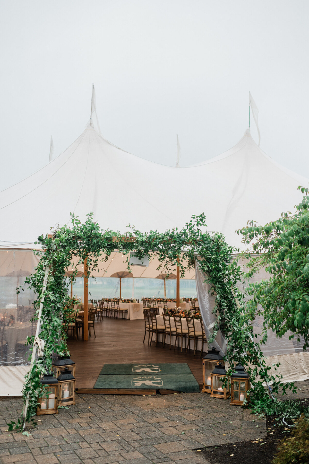 A sailcloth wedding tent set up at Spring Lake Golf Club, with an ivy-covered entrance and wooden lanterns lining the pathway