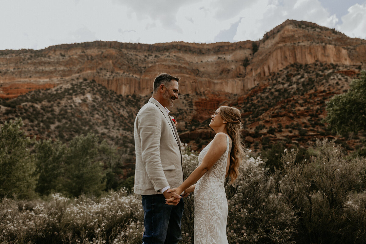 bride and groom holding each other in front of the red rocks in the Jemez Mountains in New Mexico