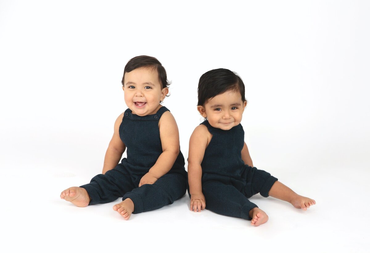 Toddlers in knit overalls sitting up