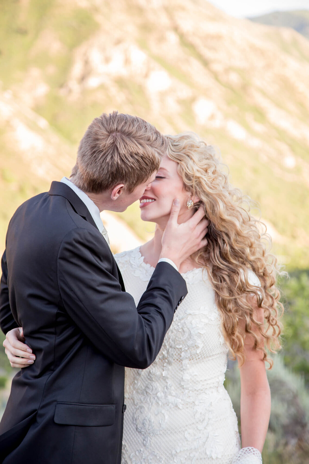 a groom kissing a curly haired bride