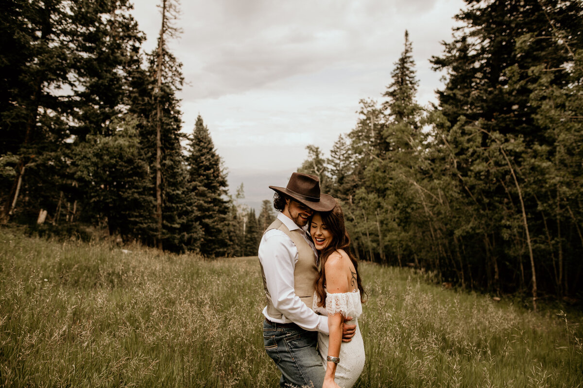newlyweds holding each other in a field of grass and the Sandia Mountain Peak in Albuquerque