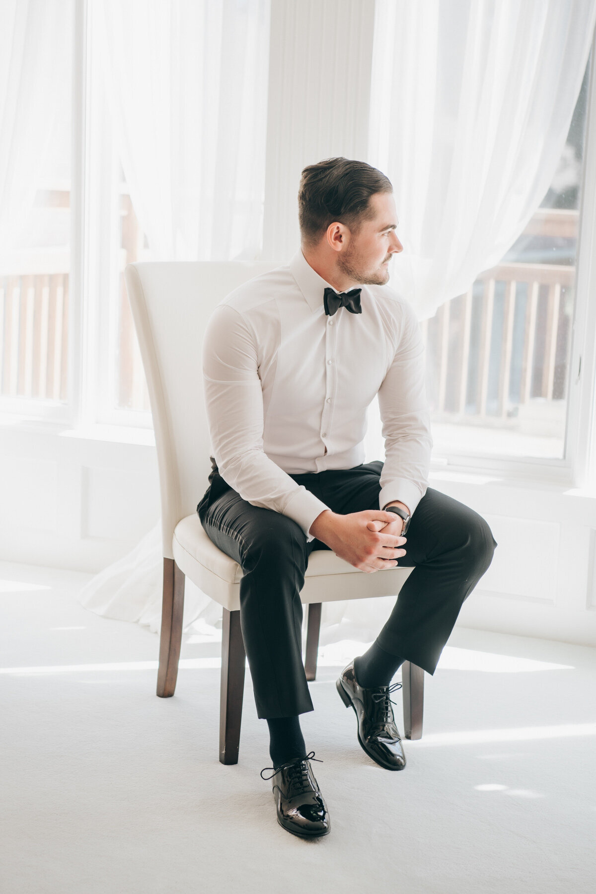 The groom in black tie attire posing for portraits on his wedding day