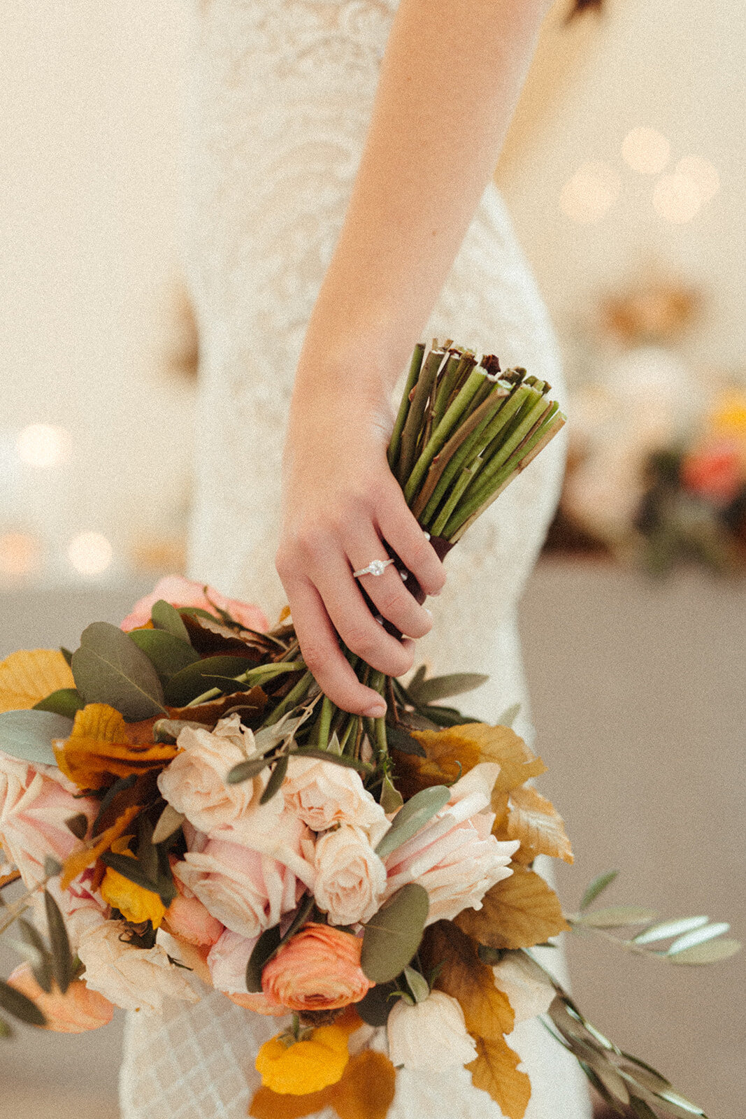Close-up of the bride holding a bouquet of flowers against her white wedding gown.