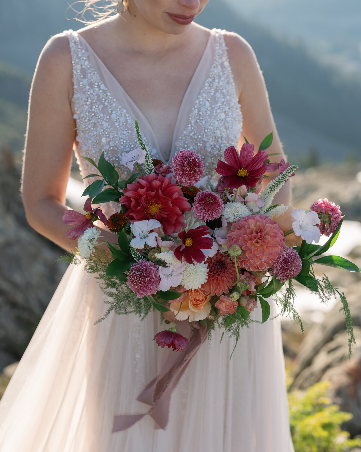 Bride holding a red, blush and peach bouquet