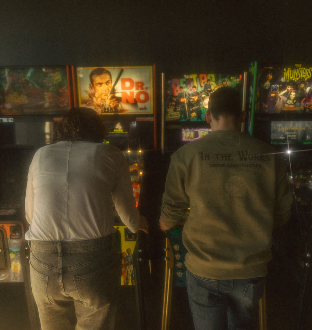 A couple playing pinball together.