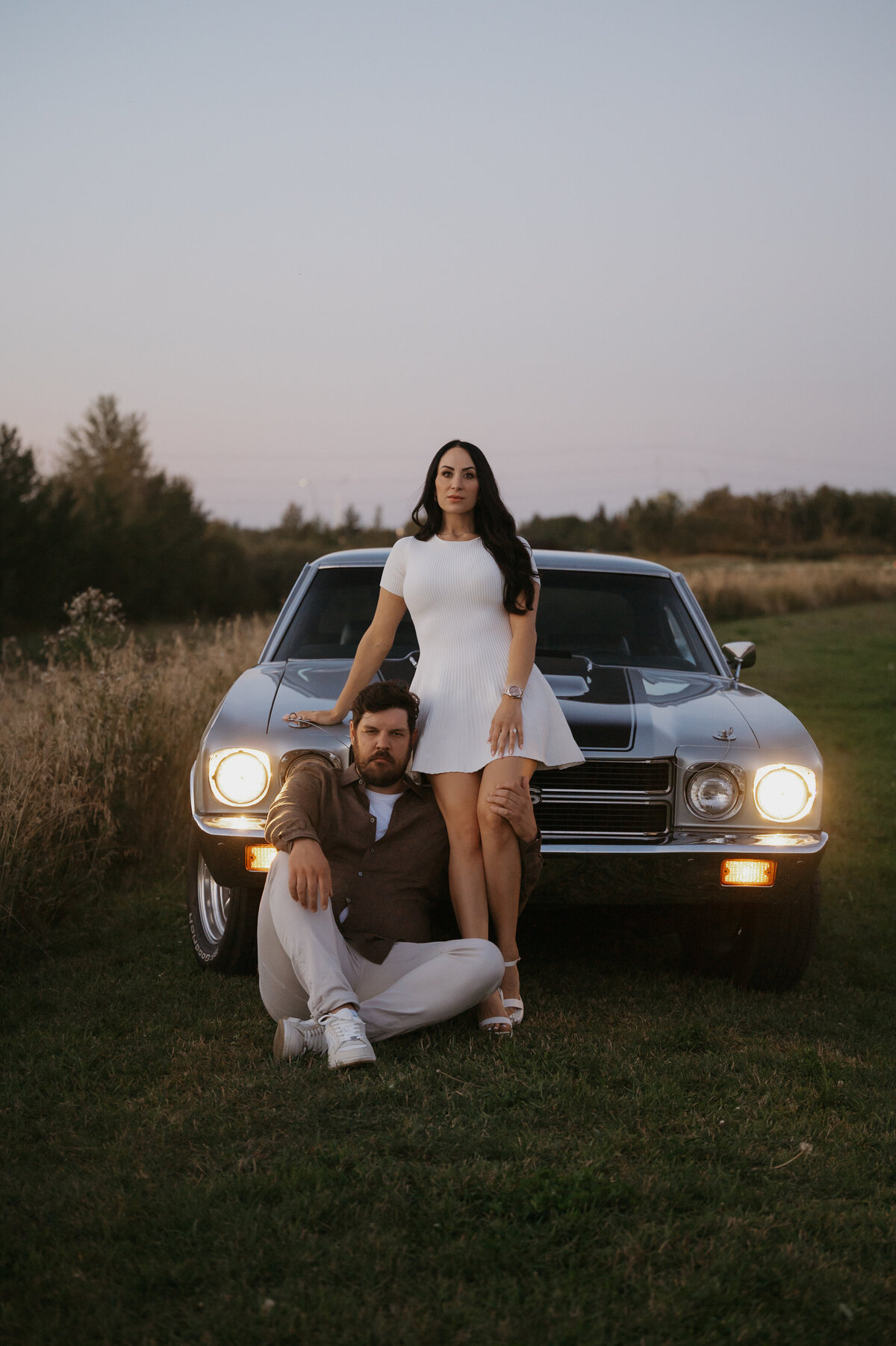 Couples poses infront of their car in a field in Edmonton Alberta