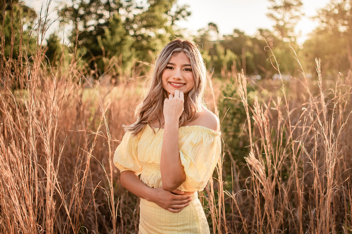 A Houston area senior stands in a field at sunrise.