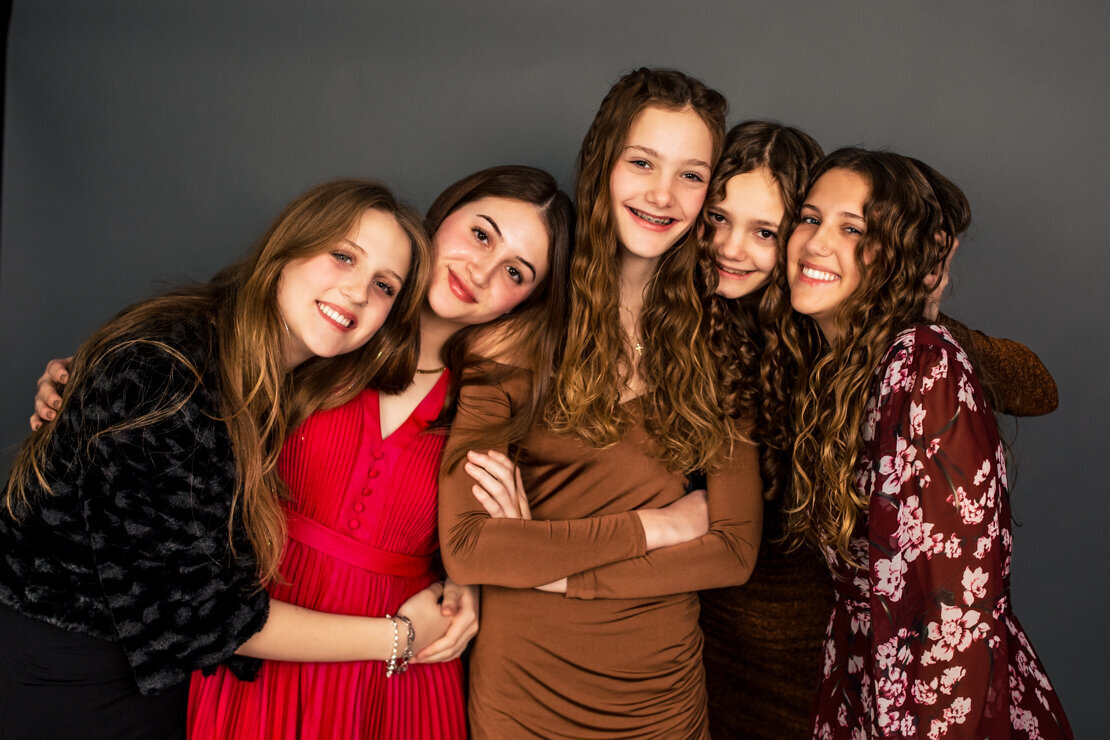 five sisters embrace in a formal portrait taken to celebrate the holiday season in Pittsburgh PA at the only family photography studio in the city.