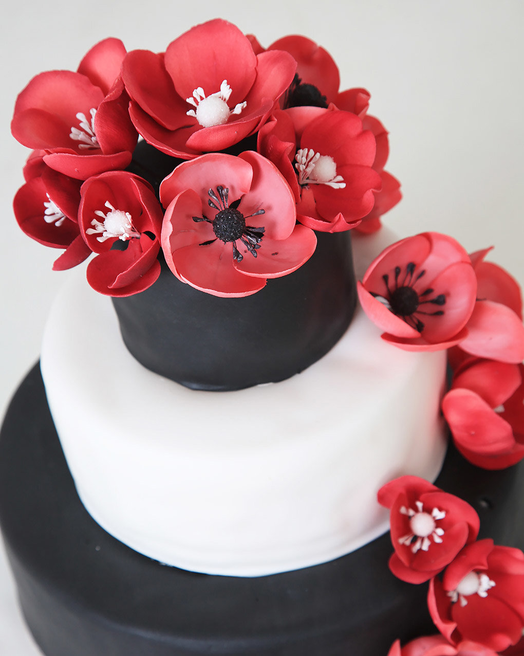 Bruidstaart van Berg's Bakery met rode bloemen en zwart-witte taarten