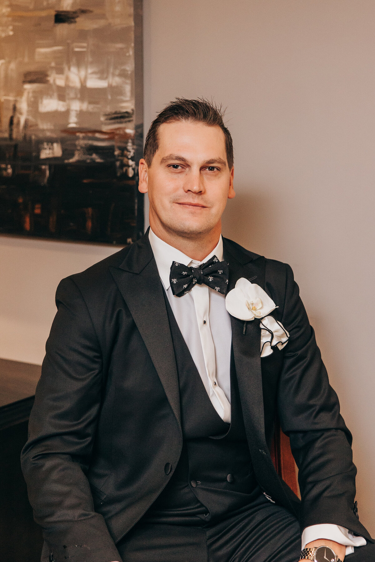 A groom in a black tux sitting and posing for portraits