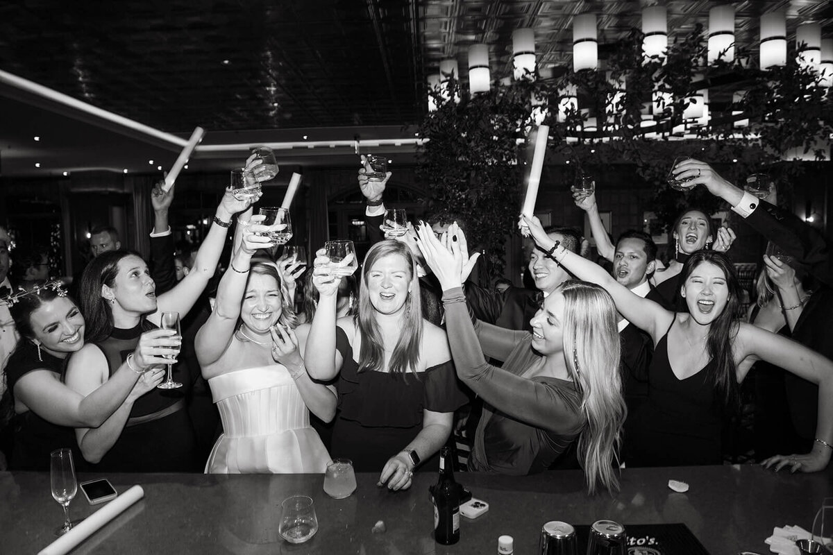 Wedding guests raising drink glasses in celebration at St. Regis Aspen, capturing a joyful and festive moment during the reception.