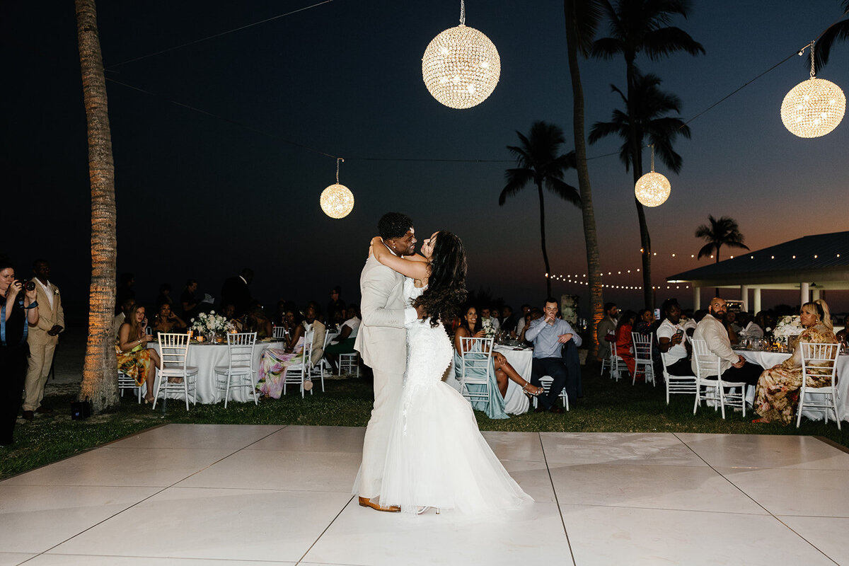 Andressa and Jonathan share their first dance under glowing lanterns and swaying palm trees at their Islamorada wedding reception. Photography by Claudia Amalia Wedding Photography.