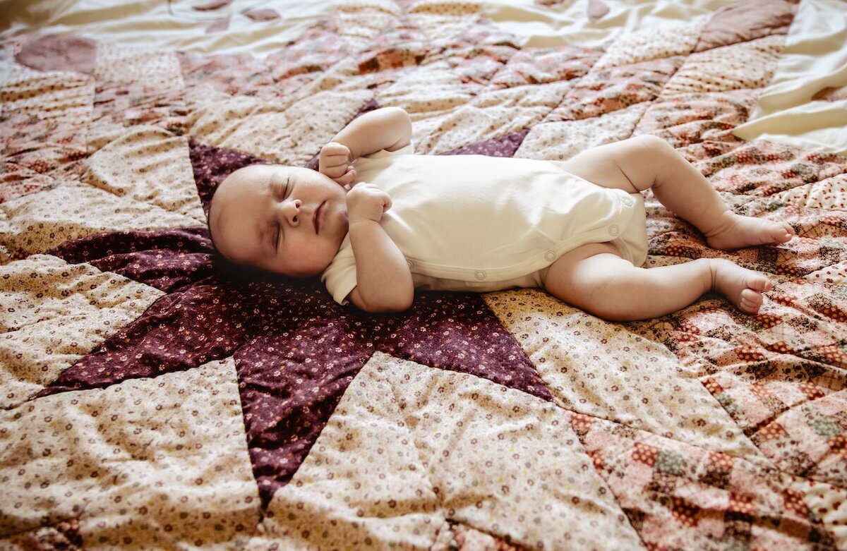 a newborn baby girl fast asleep on a handmade quilt
