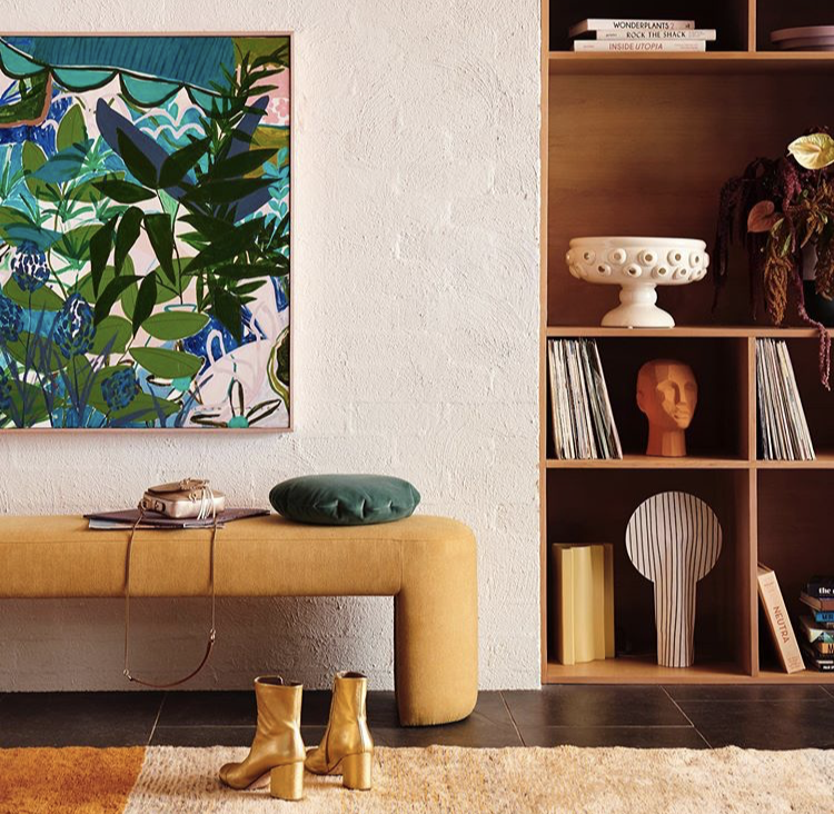 Bookshelf with styled objects and large artwork beside mustard bench in residential Melbourne home by Lisa Hunter Interiors.