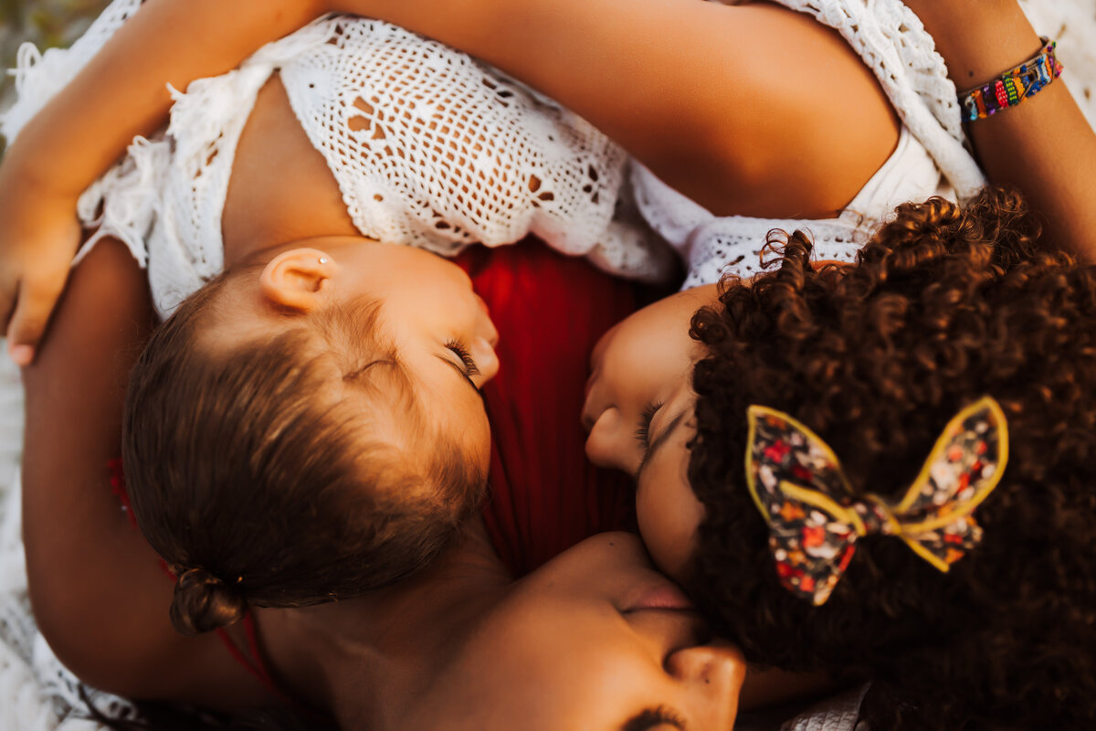 beautiful portrait of a mother ;aying on the ground at the beach cuddling on a cold fall day