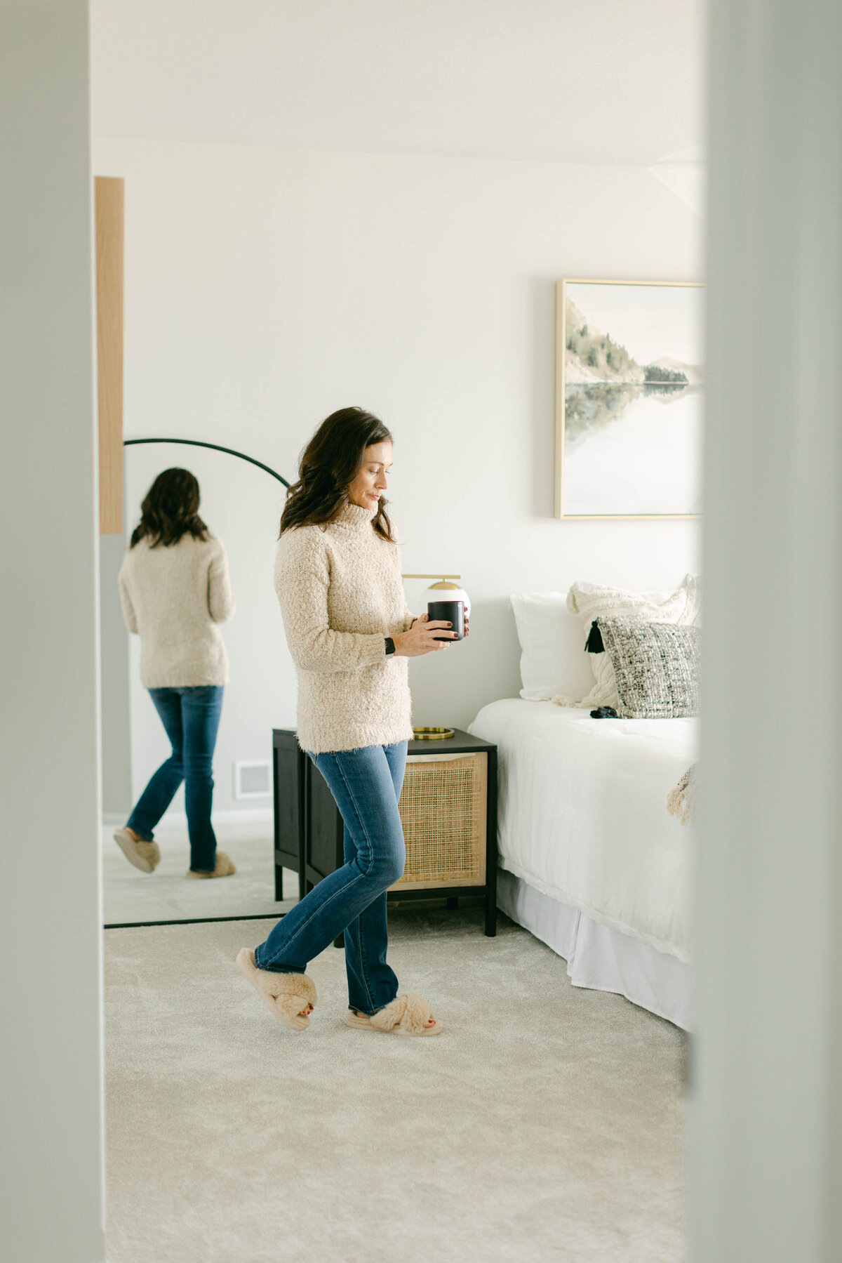 a woman walking in a bedroom while holding a candle