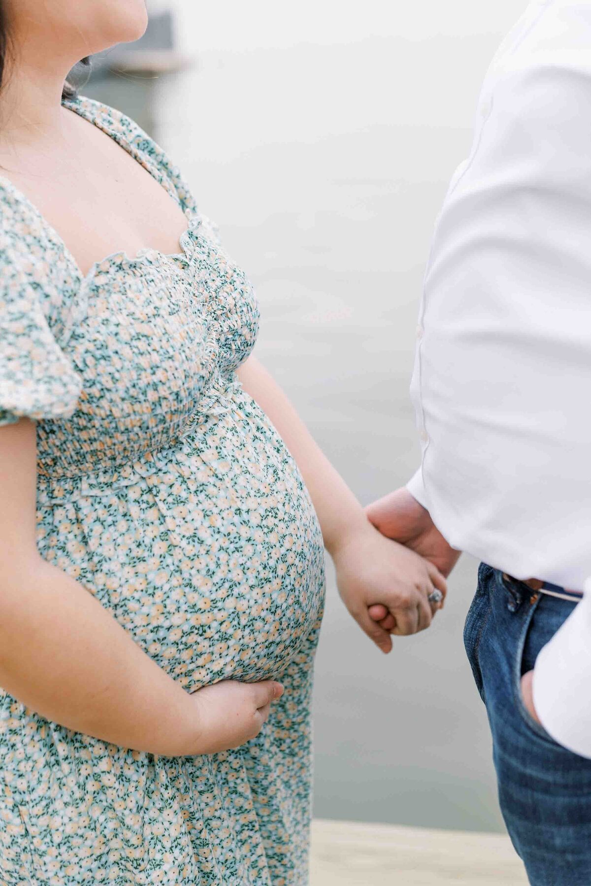 Richmond Maternity photography | Close up film image of a pregnant mother's belly as she holds hands with her husband by the waterfront by Jacqueline Aimee Portraits