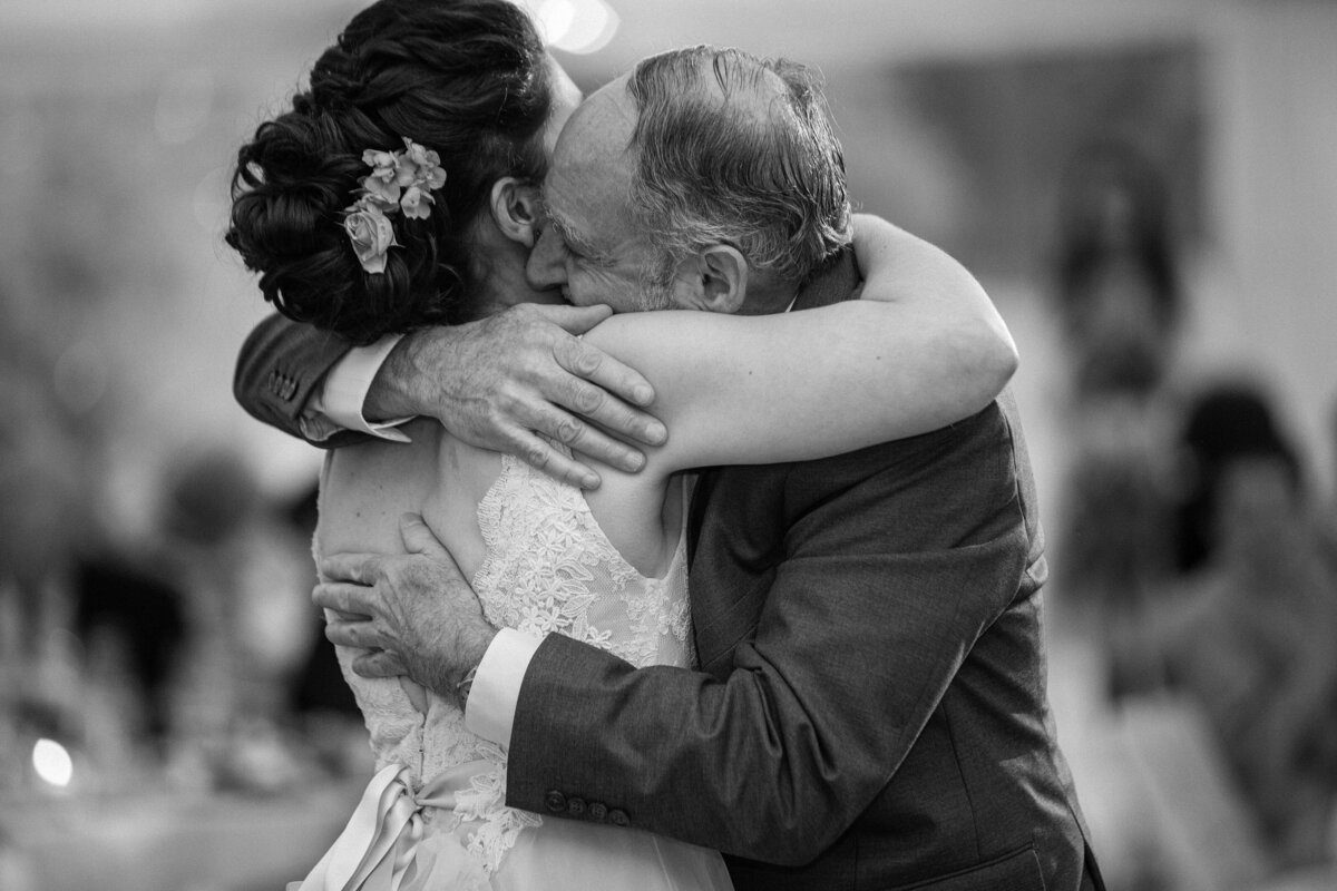 Father embraces bride after dancing together.